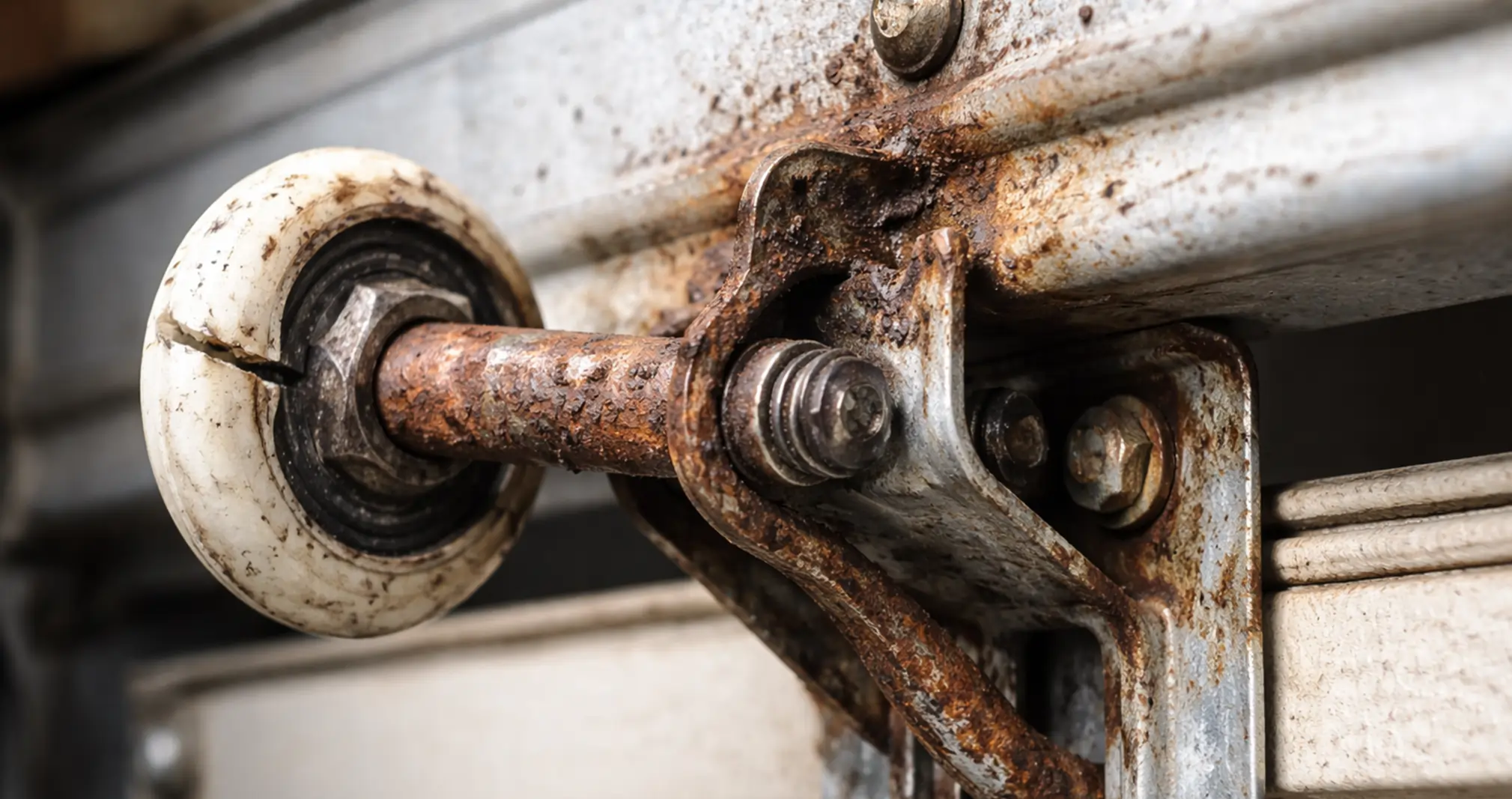 Damaged garage door roller with cracks and rust needing repair